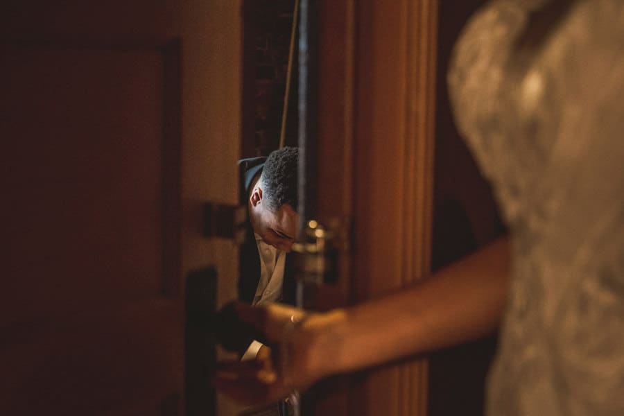 A bride and groom, one being a nurse, looking at each other through a door.