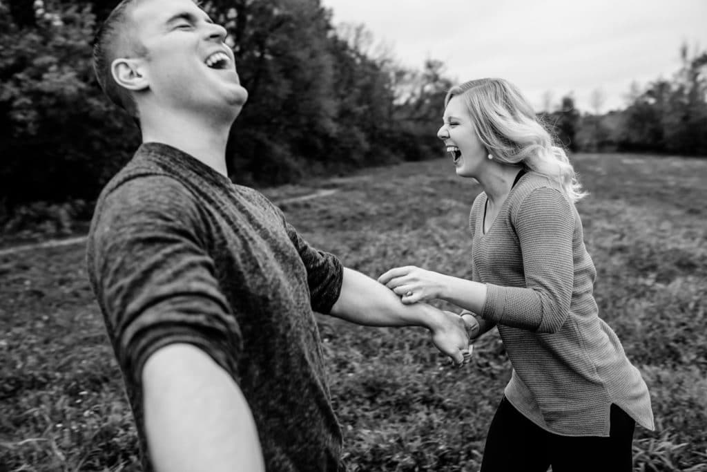 Black and white photo of a couple laughing in a field.