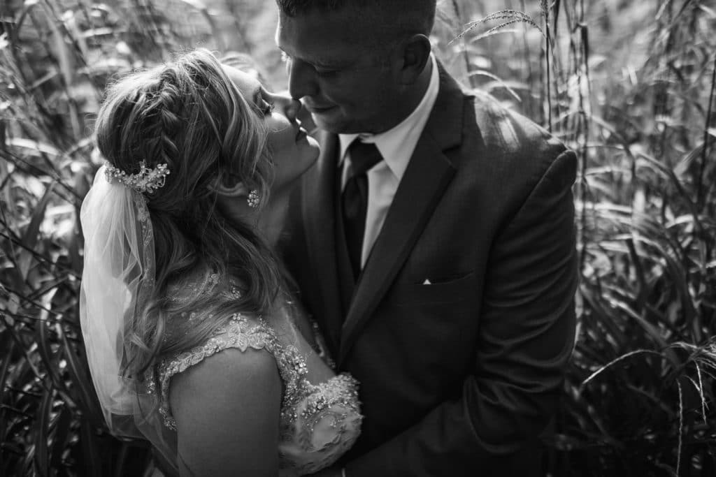 Black and white photo of a Marine wedding couple in tall grass.