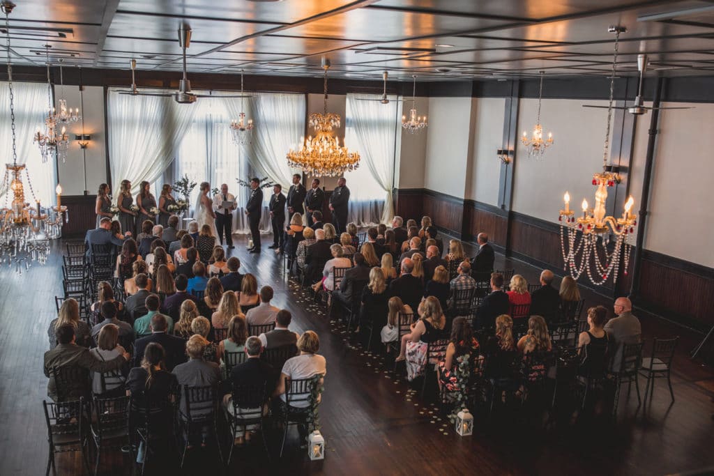 A Downtown La Crosse wedding ceremony in a luxurious large room with elegant chandeliers.