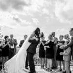 Black and white photo of bride and groom kissing on a deck.