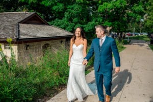 A bride and groom walking down a path in front of a building.
