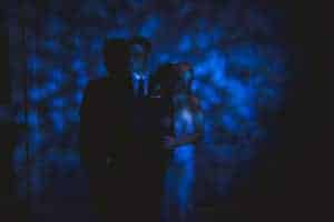 A couple embracing in front of a blue light at their dog wedding.