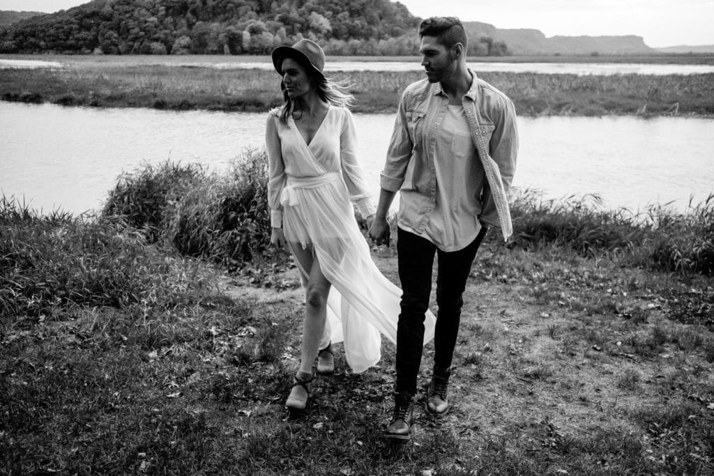 Black and white photo of a couple walking by a river.