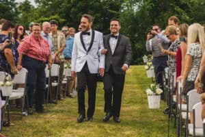 Two men walking down the aisle at a wedding.