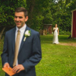 A bride and groom standing in front of a red barn.