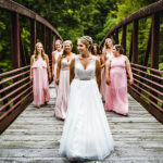 A bride and her bridesmaids walk across a bridge.