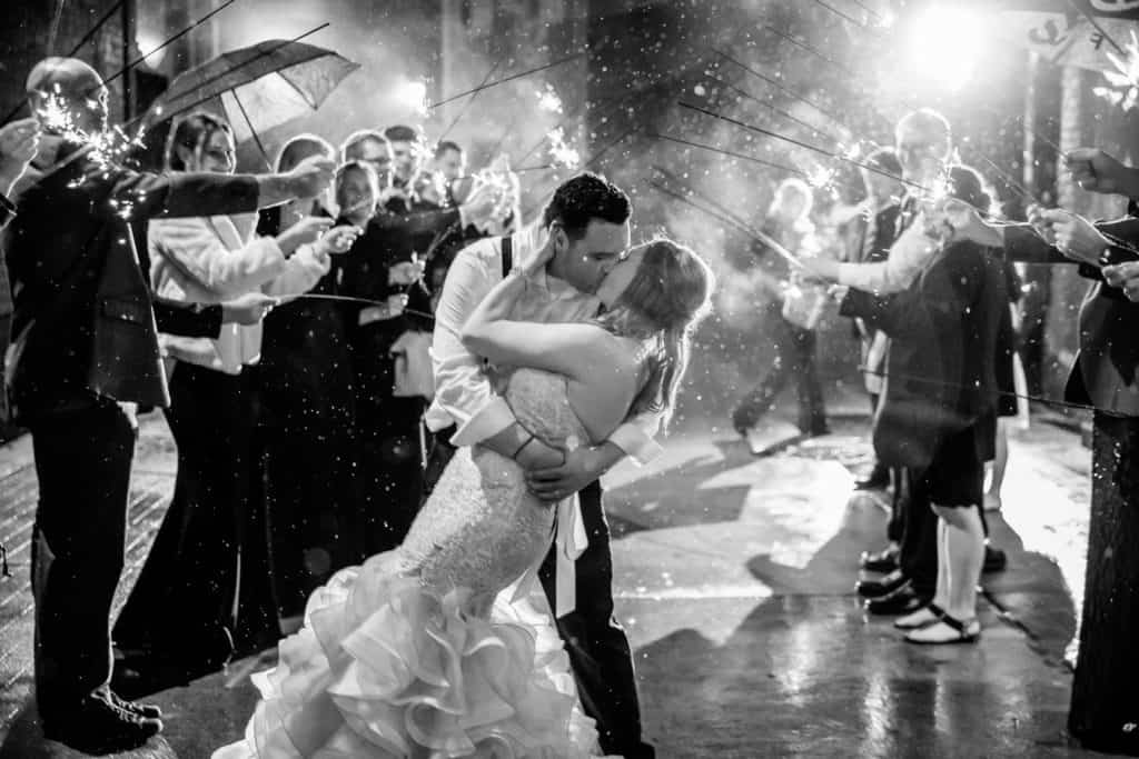 A bride and groom kissing in the rain at The Court Above Main, surrounded by sparklers.