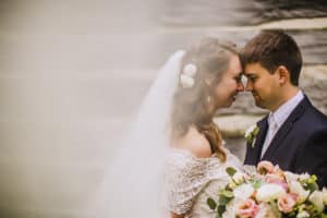 A Norskedalen wedding with a bride and groom embracing in front of a wooden wall.