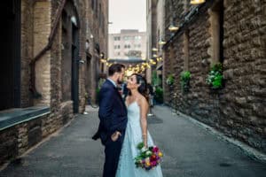 A bride and groom standing in an alleyway.