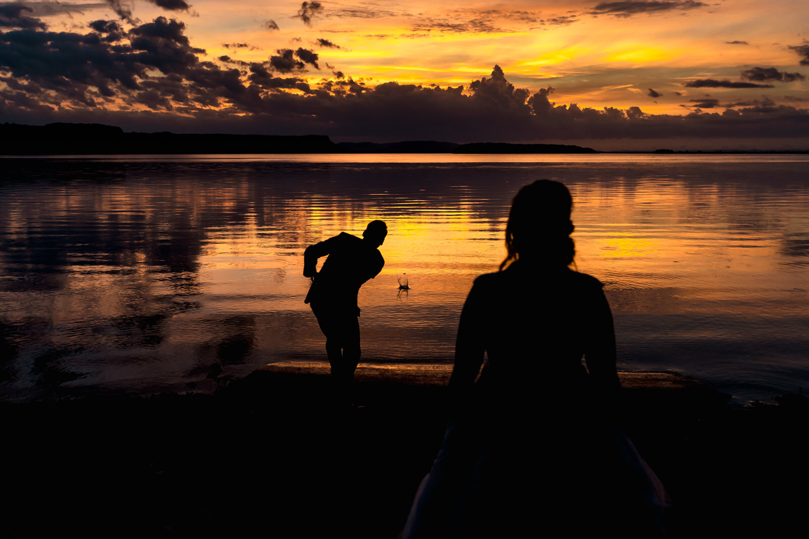 Silhouette of a bride and groom at sunset.
