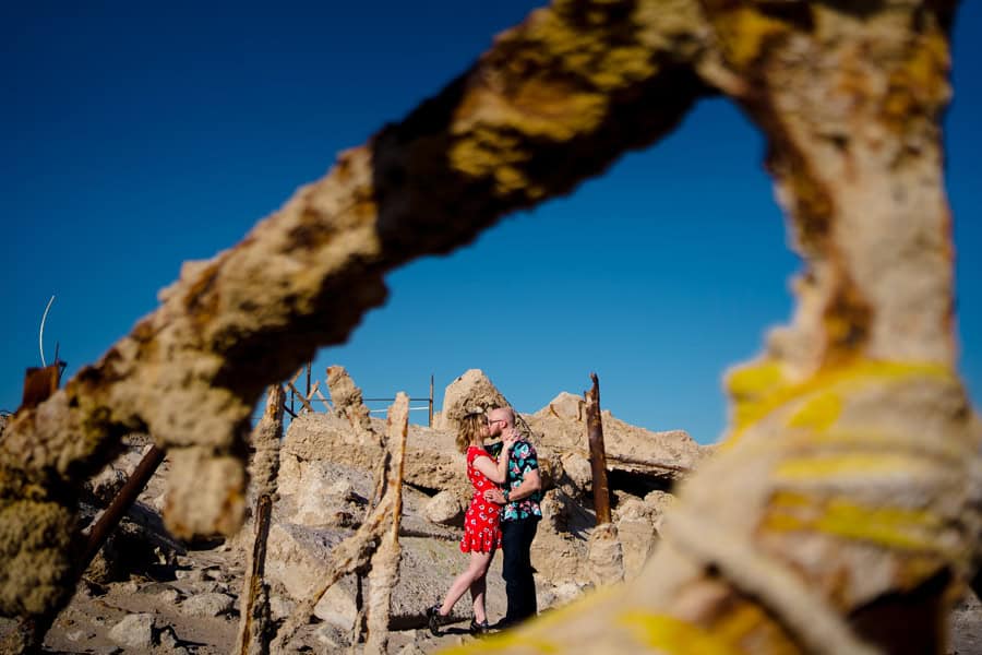A couple is posing in front of a pile of rocks.