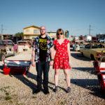 A man and a woman standing in front of a bunch of old cars.