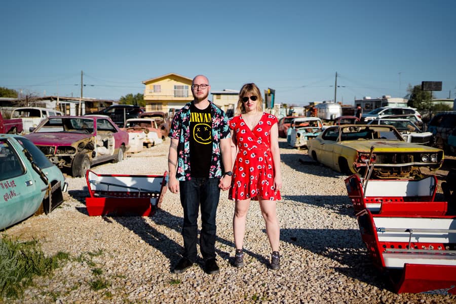 A man and a woman standing in front of a bunch of old cars.