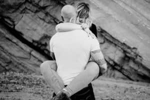 A black and white photo of a man hugging a woman.