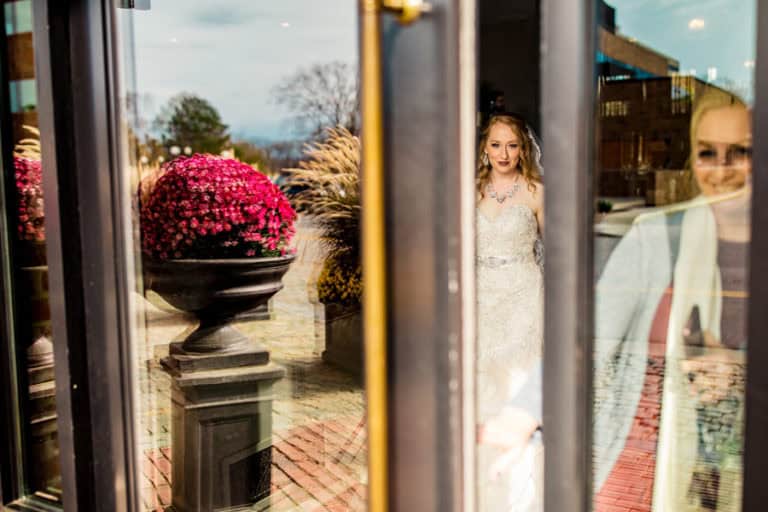 A bride is standing in front of a glass door.