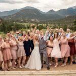 A group of bridesmaids and groomsmen pose for a photo in the mountains.