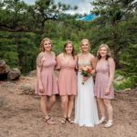 The bride and her bridesmaids pose for a photo in the mountains.
