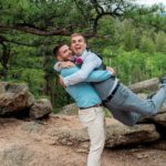 Two grooms hugging each other in the woods.
