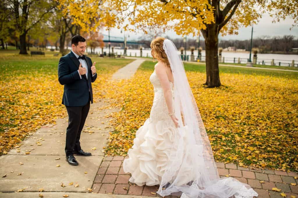 A bride and groom looking at each other in the fall.