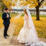A bride and groom looking at each other in the fall.