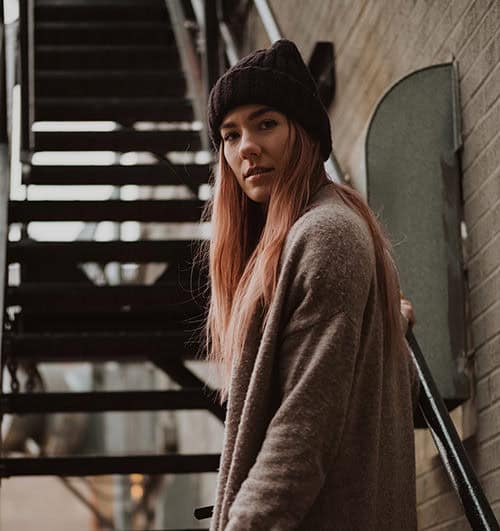 A woman wearing a beanie standing on a stairway.
