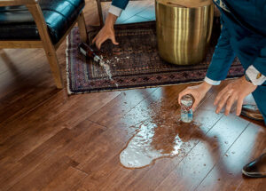 A man pouring water on a wooden floor.
