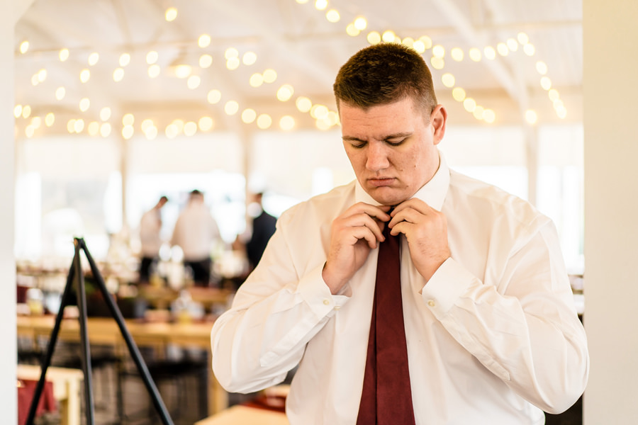 A man adjusting his tie at a wedding.
