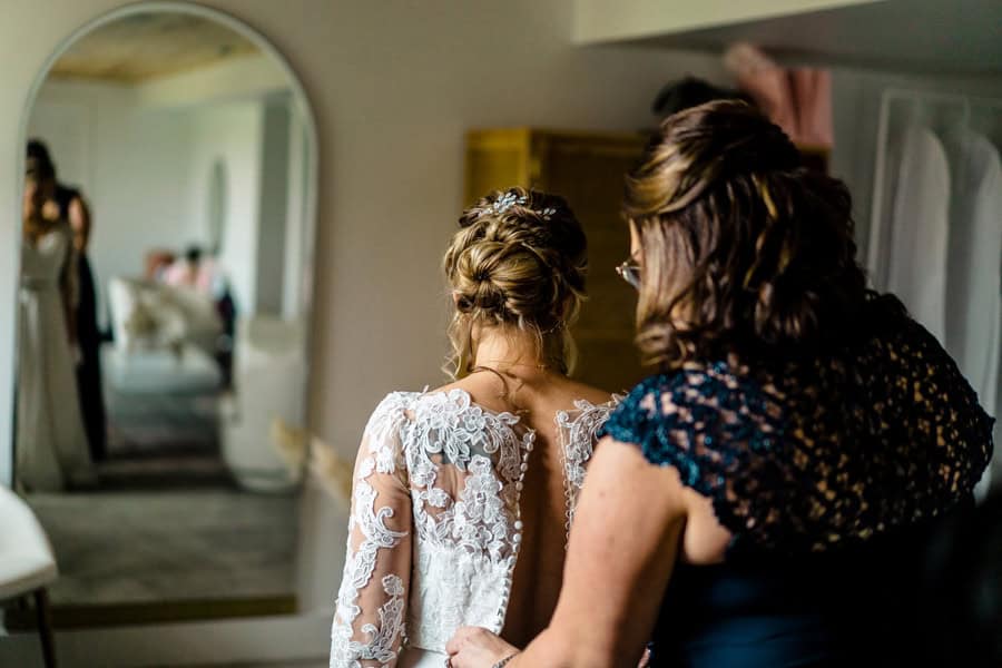 A bride is getting ready in a room with a mirror.