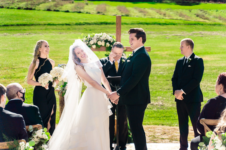 A bride and groom exchange vows in a field.