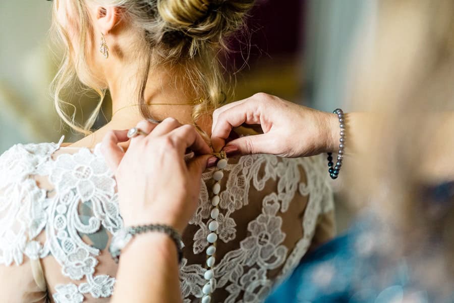 A woman is putting on her wedding dress.