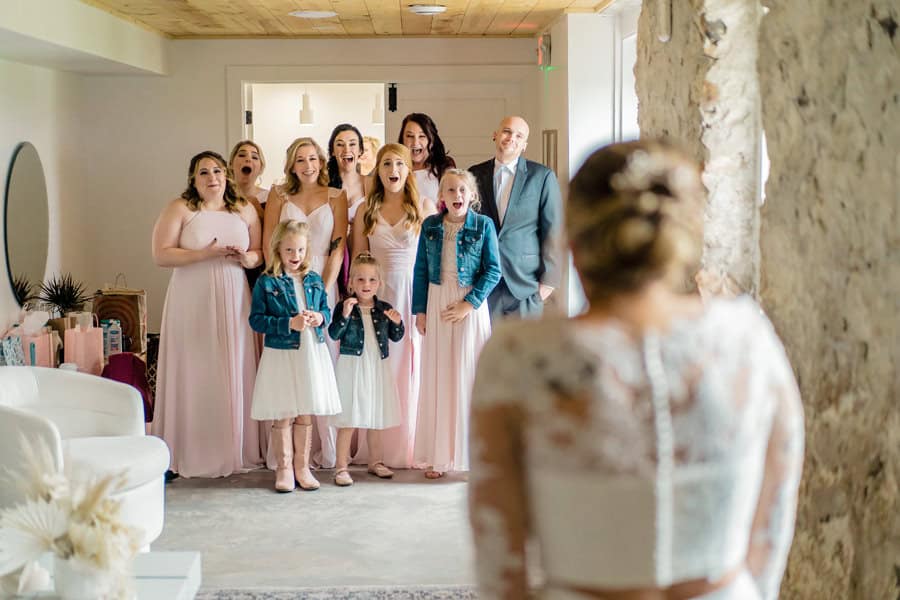 A bride and her bridesmaids are standing in front of a mirror.