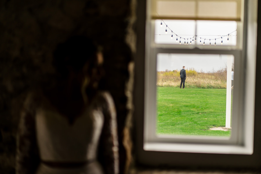 A bride and groom looking out of a window at a field.