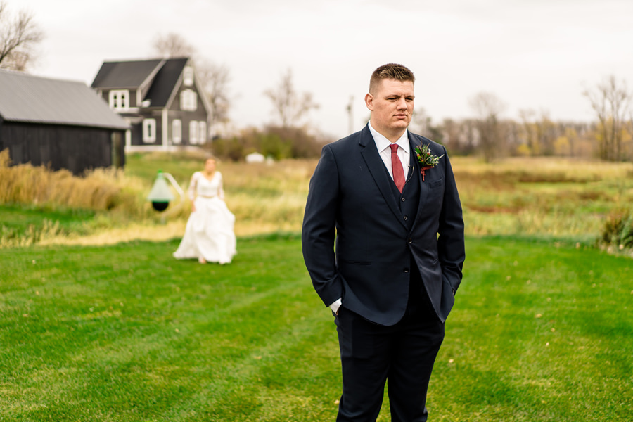 A bride and groom standing in front of a barn.