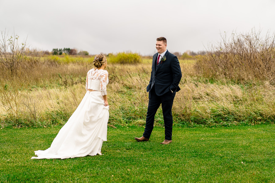 A bride and groom standing in a grassy field.