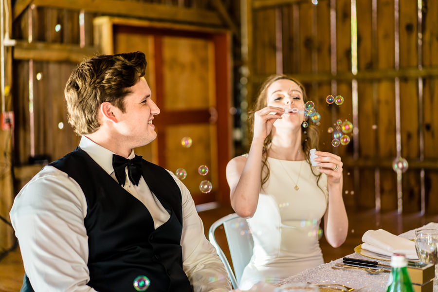 A bride and groom blowing bubbles at their wedding reception.