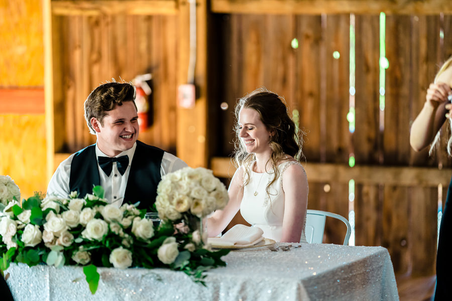 A bride and groom smiling at each other at their wedding reception.