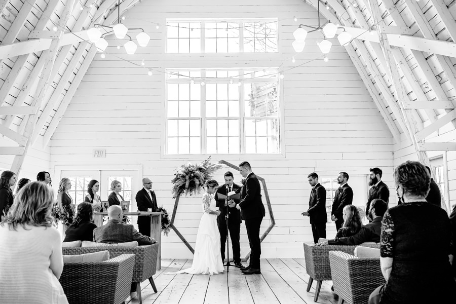 A black and white photo of a wedding ceremony in a barn.