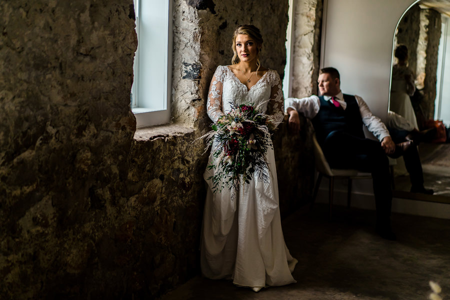 A bride and groom standing in front of a window.