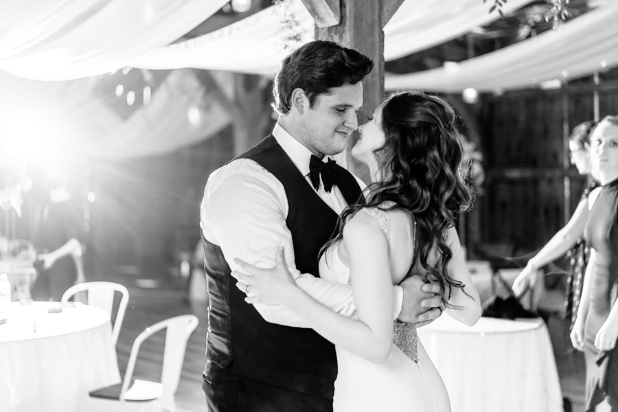 A bride and groom sharing their first dance in a barn.
