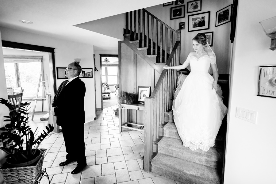 A bride and groom standing on the stairs of a house.