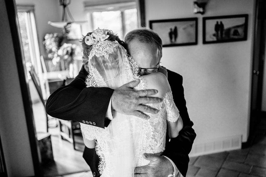 A black and white photo of a bride hugging her father.