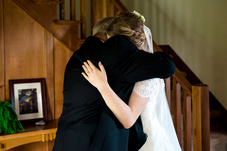 A bride and groom hugging in front of a staircase.