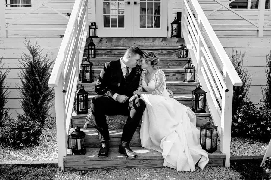 A bride and groom sit on the steps of a house.