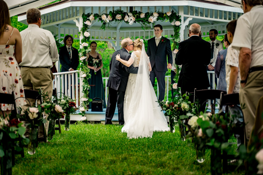 A bride and groom kissing under a gazebo.