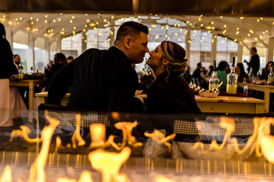 A couple kissing in front of a fire pit.