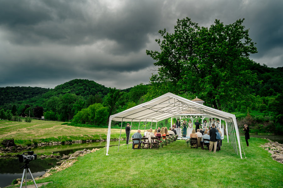 A wedding ceremony under a tent in the middle of a field.