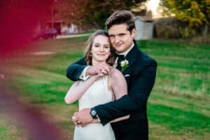 A bride and groom hugging in a field.