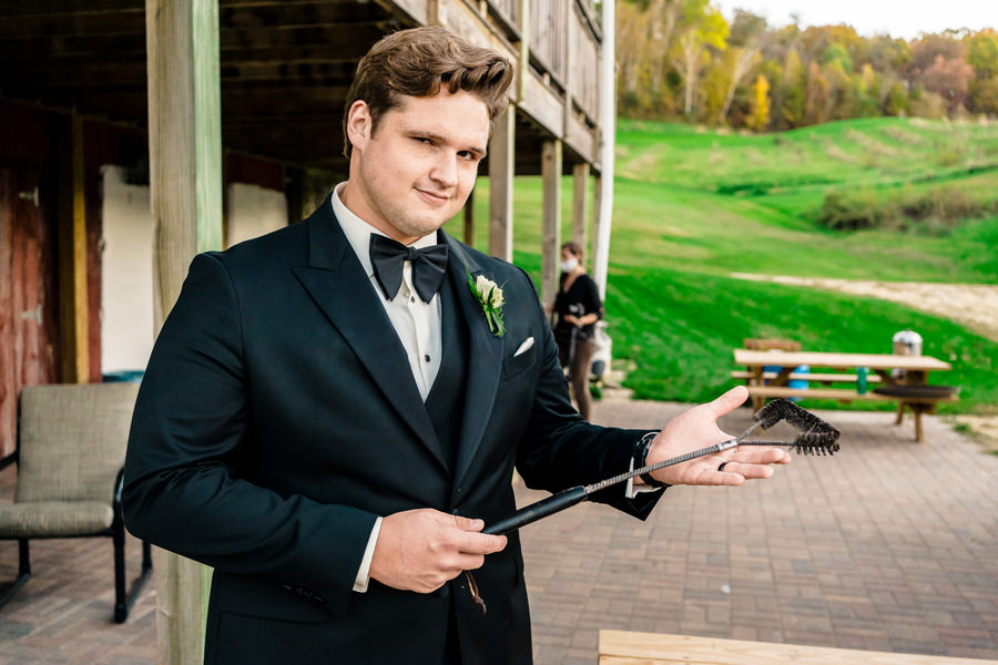 A groom in a tuxedo holding a knife.