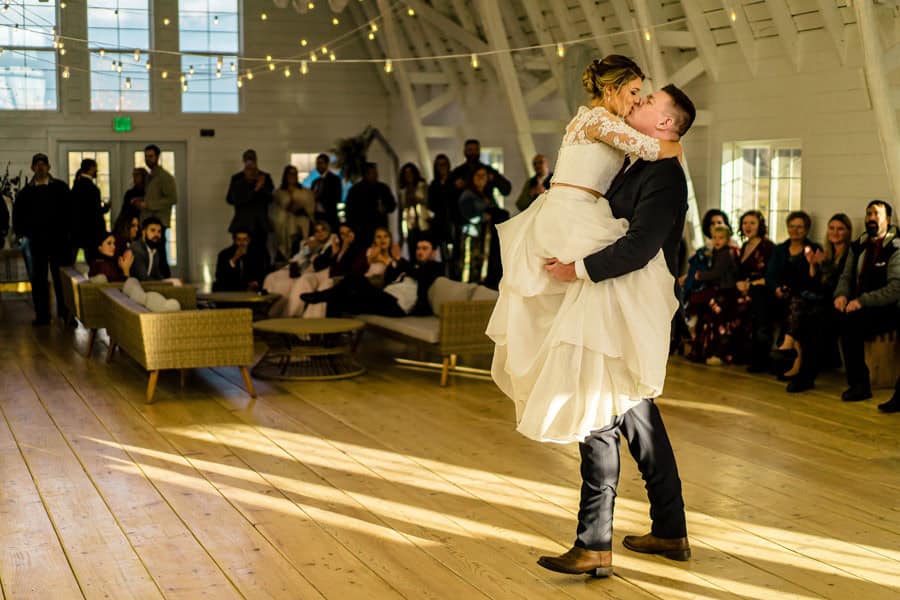 A bride and groom sharing their first dance in a barn.